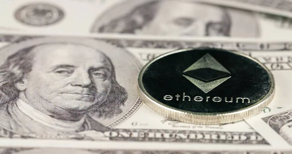 Cryptocurrency silver Ethereum coin on a hundred usd dollars bills
